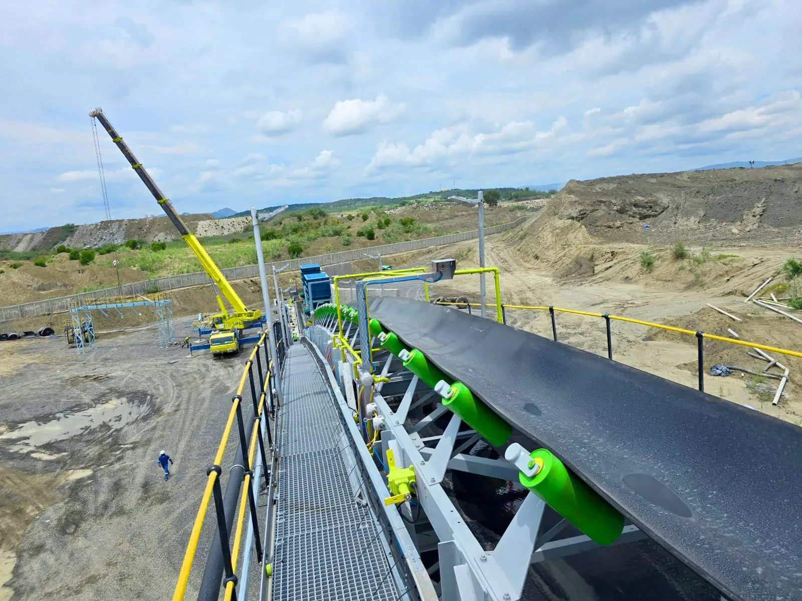 Conveyor installation with green CRS idler rollers carrying material across a mine site